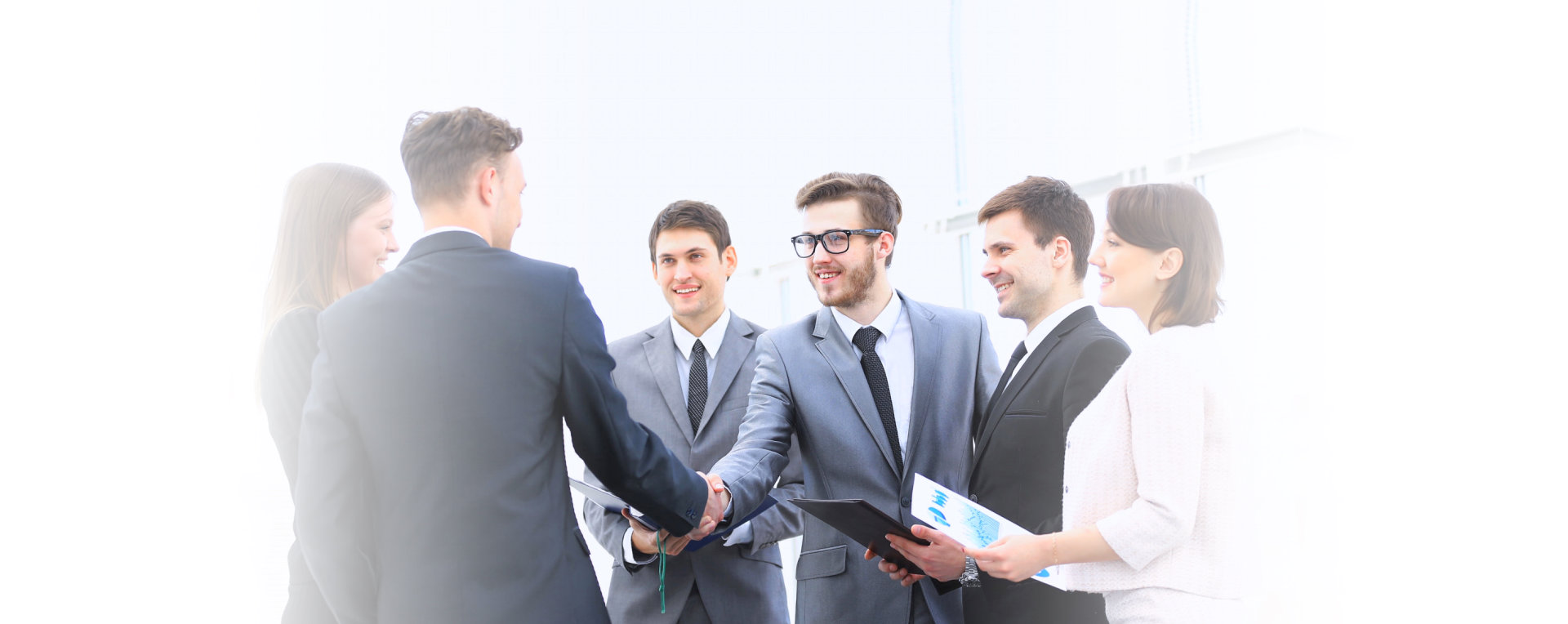 Two company owner shaking hand while smiling and their staffs